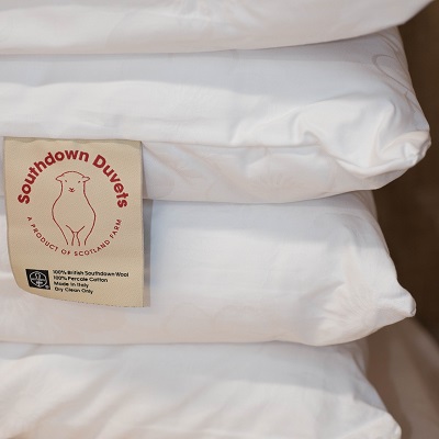 Pile of Southdown Duvet pillows with label showing 100% British wool 100% Percale cotton made in italy dry clean only