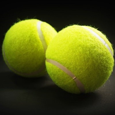two bright green tennis balls on black background